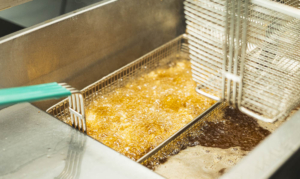 Panierte Hähnchenstücke werden in einer professionellen Fritteuse goldbraun frittiert
